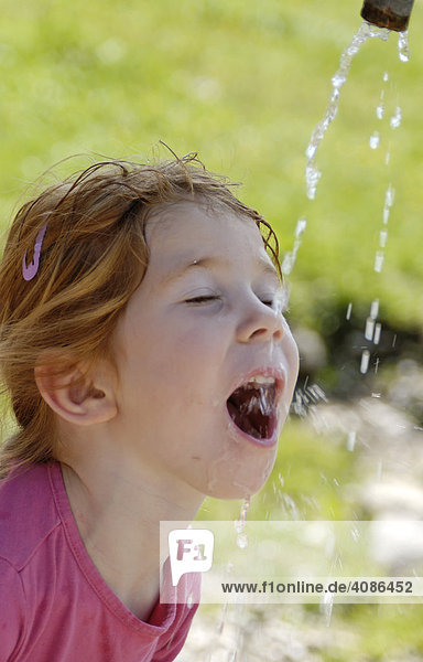 Kind beim wasser trinken aus einem Brunnen Erfrischung