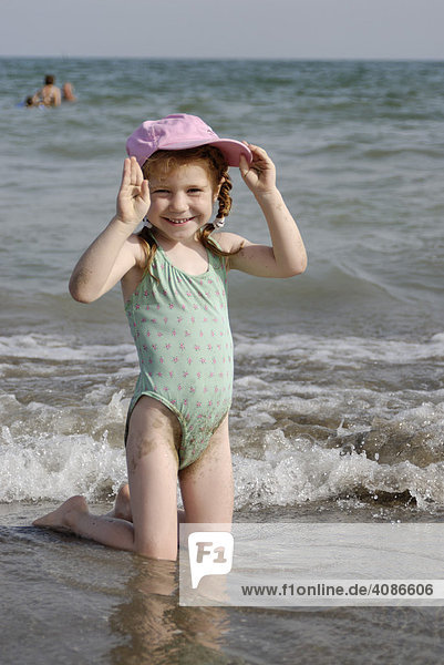 Kleines Mädchen liegt im Sand Strand am Meer