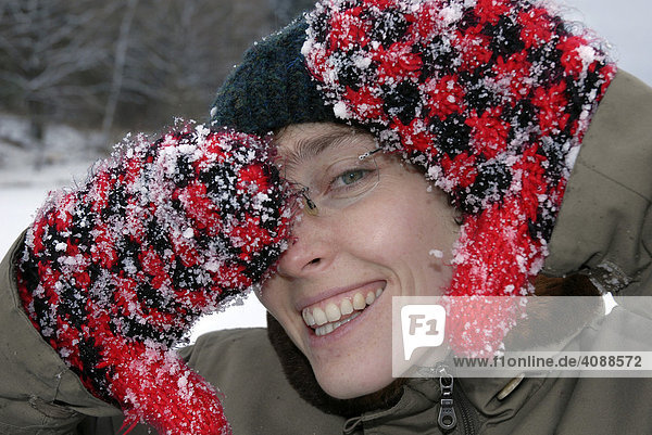Frau zeigt schneebedeckte Fäustlinge