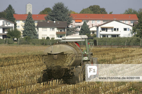 DEU  Mannheim  10.10.2005  Bauer beim Jauche verteilen auf einem Feld mit Bebauung