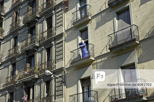 Weisshaarige Frau steht im Morgenmantel auf ihrem Balkon  Hausfassaden  Barcelona  Katalonien  Spanien Hausfassaden