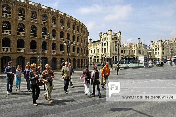 People crossing the street on a zebra crossing in front of a bullfight arena and the main station  Valencia  Spain