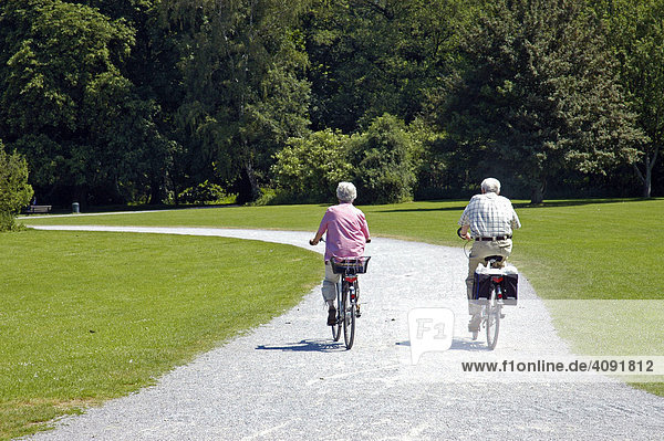 Two senior citizens ride bicycles in the park of castle Herten  Ruhr area  North Rhine-Westphalia  NRW  Germany |