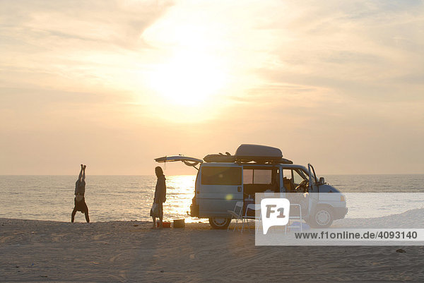 Junge Menschen geniessen den Sonnenuntergang mit Wohnmobil am Strand am Atlantik  Algarve  Portugal
