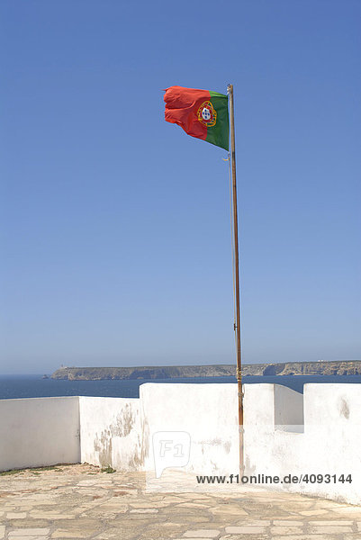 Fahne auf dem Fort Fortaleza de Sagres  Nationaldenkmal auf dem Hochplateau Ponta de Sagres  49 Meter über dem Meeresspiegel in der Nähe des Ortes Sagres in der Algarve von Portugal im Hintergrund Cabo de Sao Vicente
