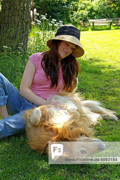 Junge Frau spielt mit Golden Retriever Hund im Garten