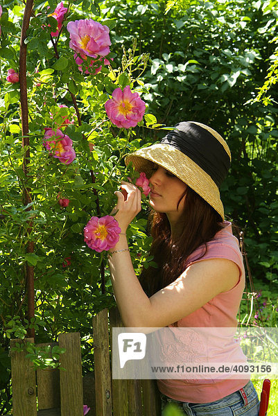 Junge Frau mit Hut riecht an einer Rose rosa marguerite hilling