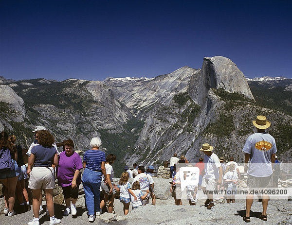 Tourist enjoy the view to the Half Dome viewed from Glacier Point  Yosemite NP  California  USA