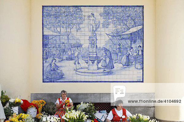 Woman selling flowers behind a azulejo (glazed tile) with a market scene  Funchal  Madeira  Portugal