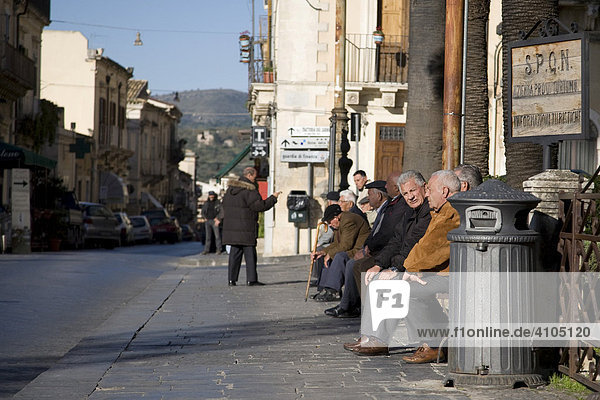 Elderly people sitting on the side of a street in Noto  Sicily  Italy