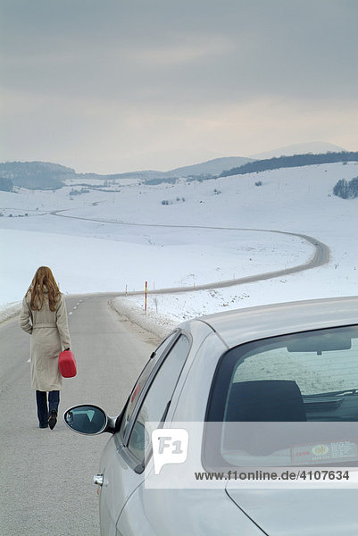 Junge Frau verlässt Wagen auf einer einsamen Landstraße auf der Suche nach Benzin