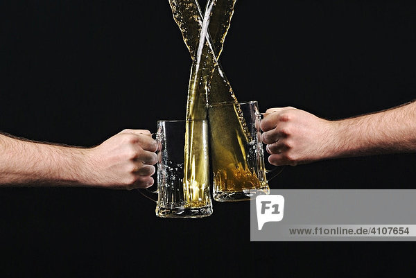 Two arms banging beer mugs together in a toast
