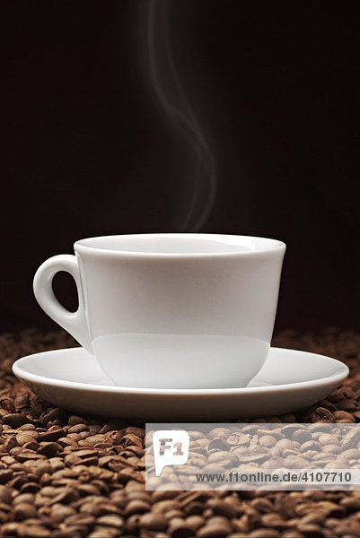 Dampfende Tasse Kaffee auf Kaffeebohnen