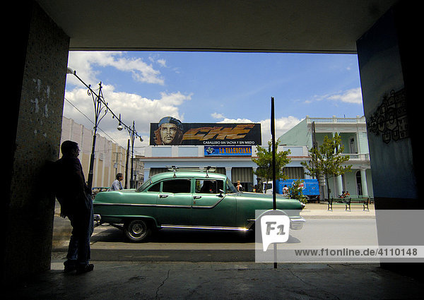 Oldtimer grün vor Gebäude mit Che Propaganda  Blick aus Durchgang  Cienfuegos  Kuba