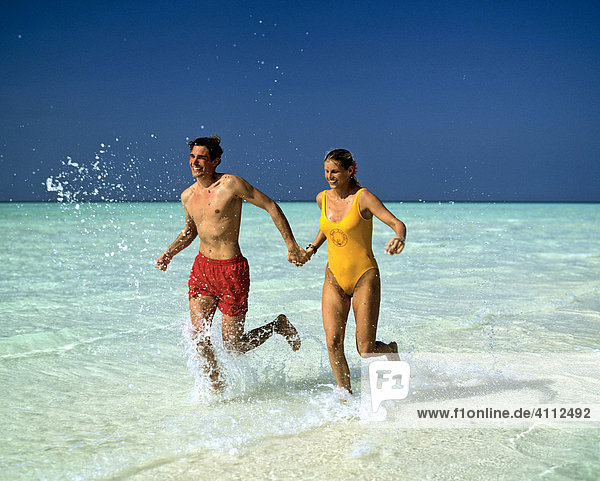 Young couple jogging through shallow water  Maldives  Indian Ocean