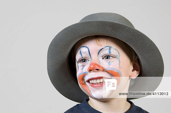 Young boy with clown-make-up and hat