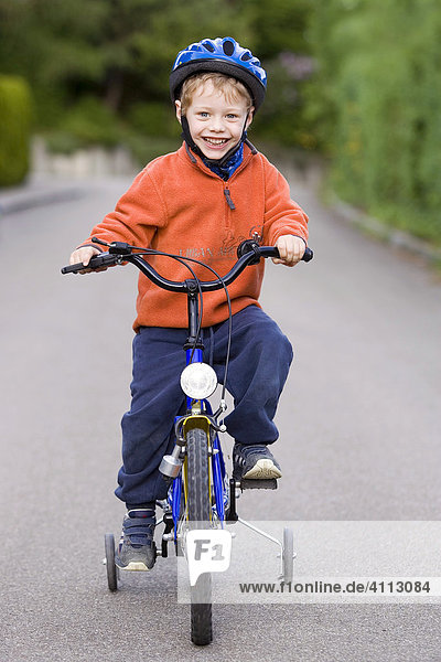 Little boy with hardhat on his bike with stabilisers