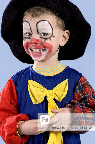 A three year old boy in the guise of a clown