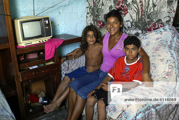 Alleinerziehende Mutter mit zwei Söhnen im Wohnzimmer ihres Hauses in der Favela Imbiribeira  Recife  Brasilien