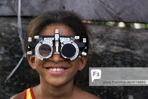 Mädchen mit brillenähnlichem Sehtestgerät in einer Favela  Recife  Brasilien