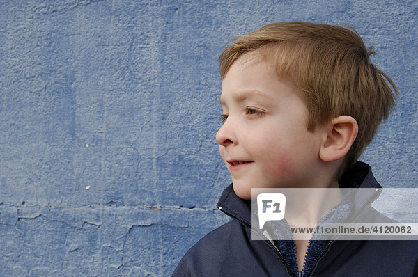 Young boy (age 5) standing in front of a blue wall