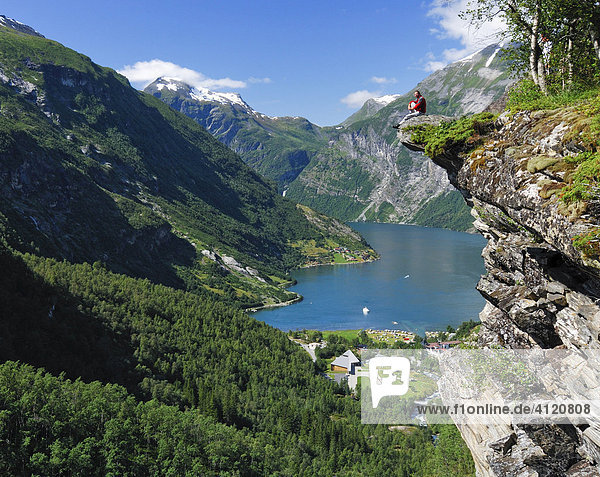 Mann sitzt auf einem Felsvorsprung  Geirangerfjord  Norwegen  Skandinavien