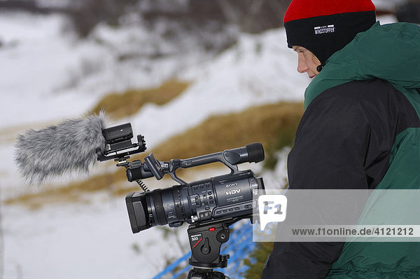 Kamerafrau mit Daunenjacke filmt  Winter  Nord Norwegen  Skandinavien