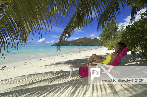 Junge Frau schläft im Liegestuhl unter Palmen  Insel Praslin  Seychellen  Afrika