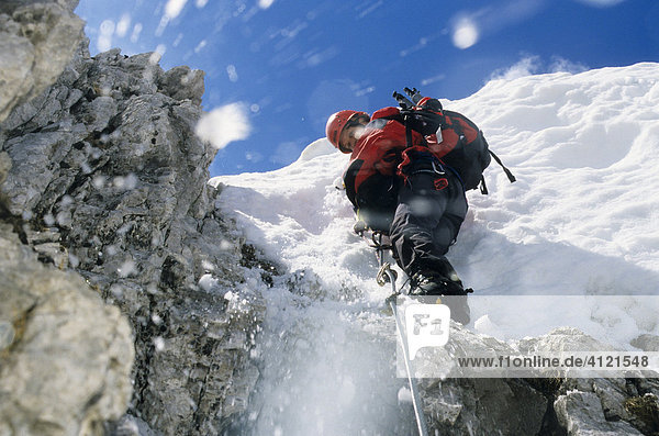Bergsteigerin klettert an einem Stahlseil über eine Schneewechte  Schnee rutscht ab und fällt herunter  Nordkette  Innsbrucker Klettersteig  Tirol  Österreich  Europa