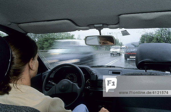 Frau sitzt am Lenkrad  fährt Auto  draußen dichter Verkehr und Regenwetter