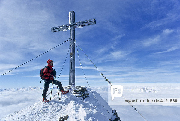 Bergsteigerin steht am Gipfel des Similaun neben dem eisernen Gipfelkreuz  Tirol  Österreich  Europa