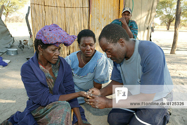 Traditional healer reading the palm of a sick patient  Sehitwa  Botswana  Africa