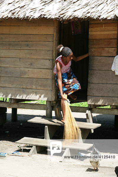Junge Frau fegt vor dem Haus  Amerindians vom Stamm der Arawaks  Santa Mission  Guyana  Südamerika