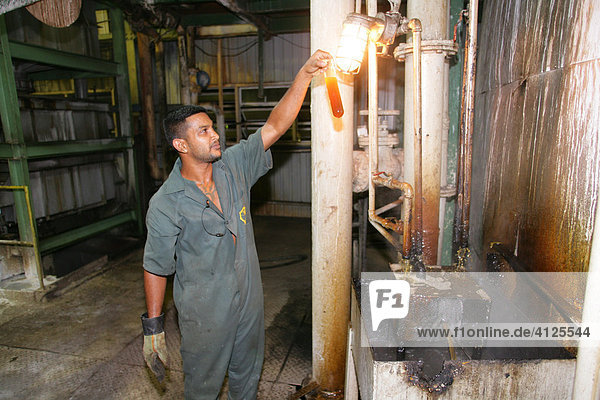 Arbeiter kontrolliert den Zuckersirup  Zuckerrohr Verarbeitung zu Demerara-Zucker  Provinz Demerara  Guyana  Südamerika