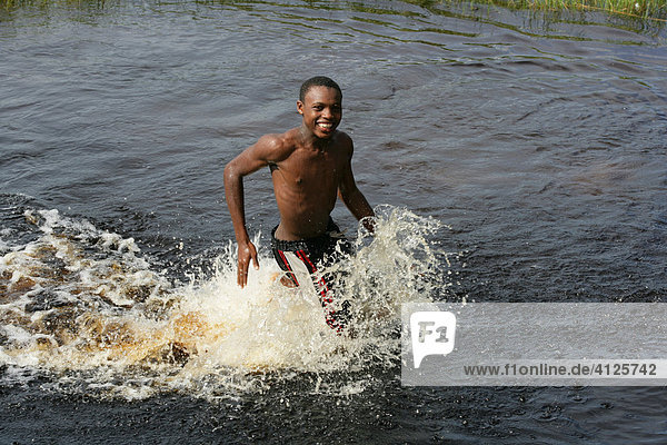 Junge läuft durch das Wasser am Lake Capoey  Guyana  Südamerika