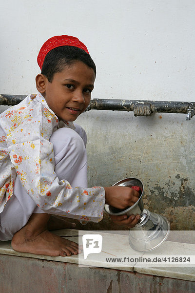 Boy cleaning ritual objects used at a shrine  Bareilly  Uttar Pradesh  India  Asia