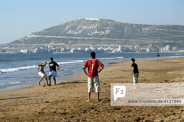 Freizeitkicker am Strand von Agadir  Berg mit dem Schriftzug Allah  el-Watan  el-Malik (Gott  die Heimat  der König)  Marokko  Afrika