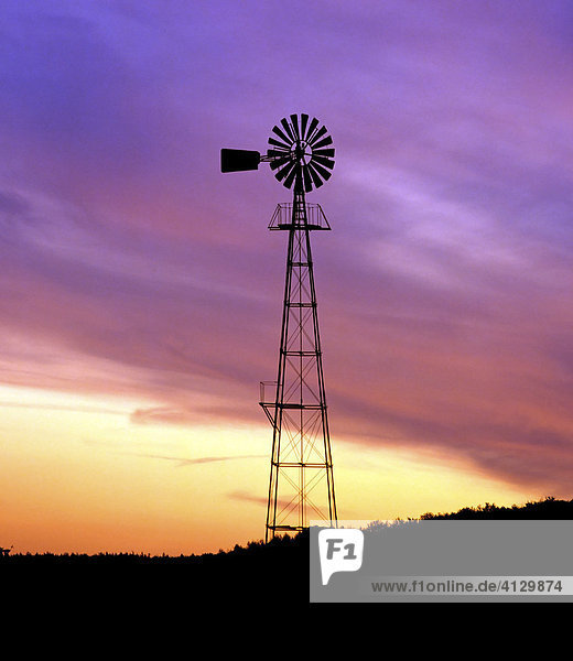 Wind pump silhouetted against colourful night sky