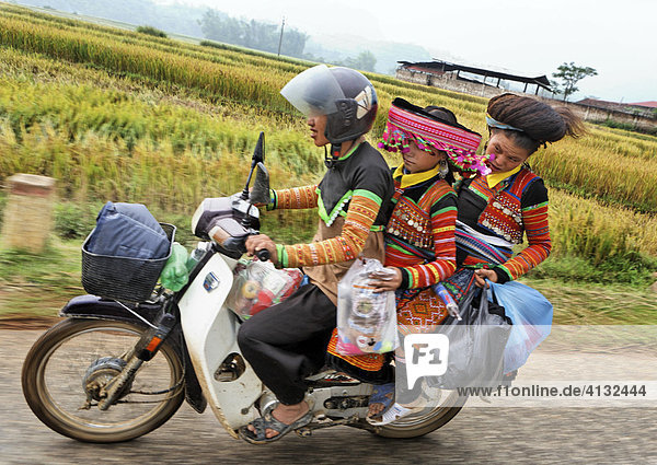 Family of the Thai People in traditional clothes riding a moped on the old route Nr 6  Vietnam  Asia