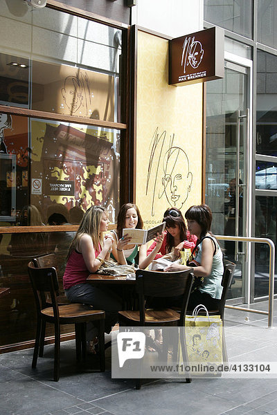 Junge Leute sitzen am Tisch vor dem Cafe Max Brenner und lesen die Speisekarte  Melbourne  Victoria  Australien