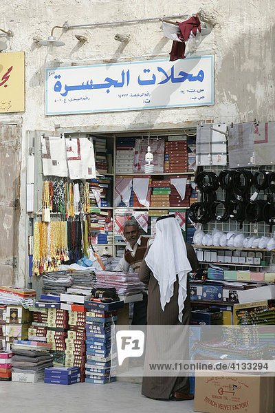 Qatar  Katar  Doha  arabischer Händler bedient Kunde  Araber in seinem Laden im Haupt Souk  Soukh Waqif.