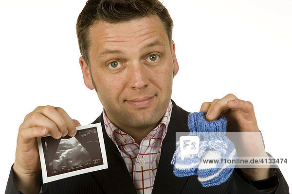 Geschäftsmann / Manager 40-jährig hält Babyschuhe und Ultraschallbild