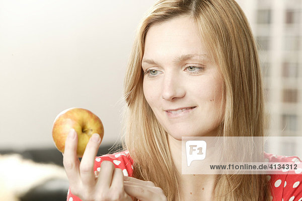 Junge blonde Frau sieht Apfel an