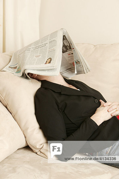 Frau im mittleren Alter mit Zeitung auf dem Kopf