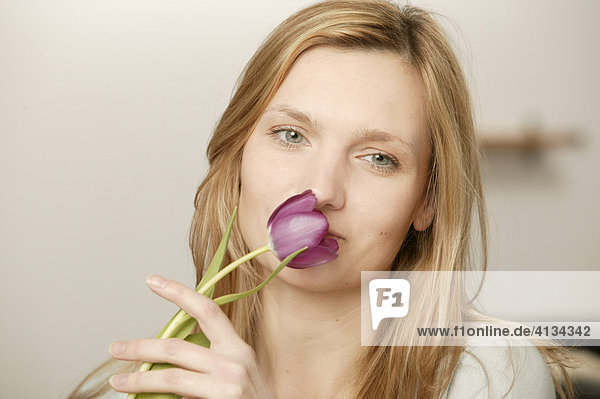 Junge blonde Frau mit lila Tulpe