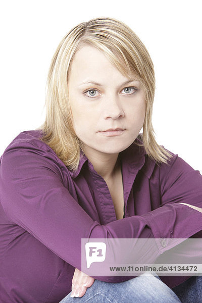 Blonde woman wearing a purple shirt  leaning on her knees