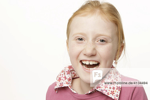 8-jähriges Mädchen mit roten Haaren lacht