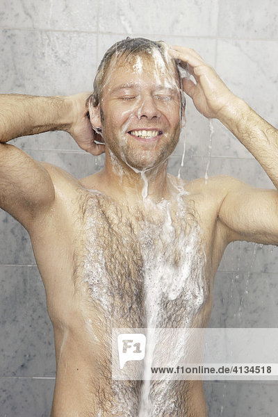 Hairy man showering  washing his hair  smiling