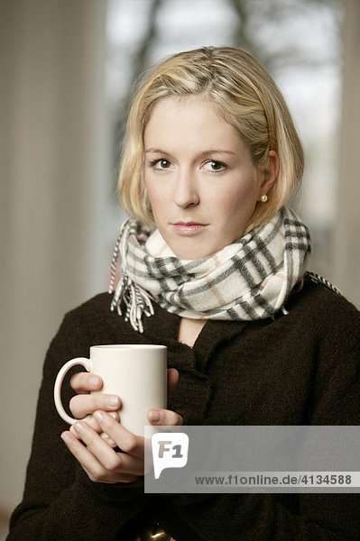 Blonde woman with a cup of tea and a scarf