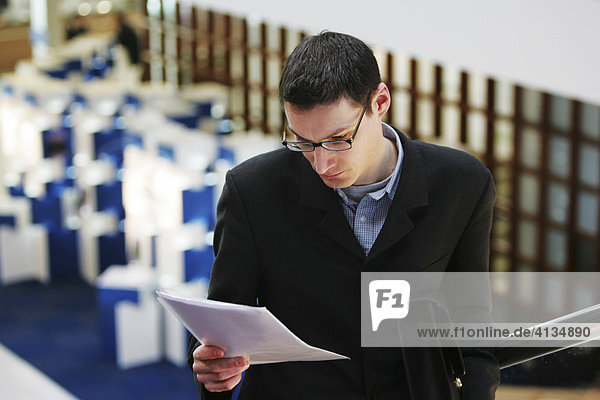 DEU Bundesrepublik Deutschland : Mann liest auf einer Messe eine schriftliche Unterlage..